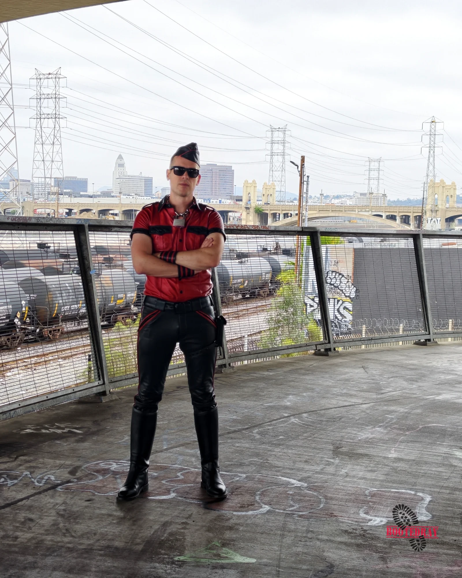 Man in red leather shirt and black pants with a hat and sunglasses
